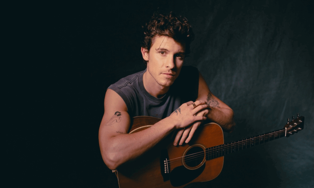 Sänger Shawn Mendes sitzt und lehnt sich auf seiner Gitarre ab