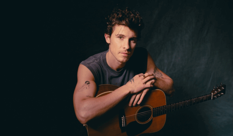 Sänger Shawn Mendes sitzt und lehnt sich auf seiner Gitarre ab