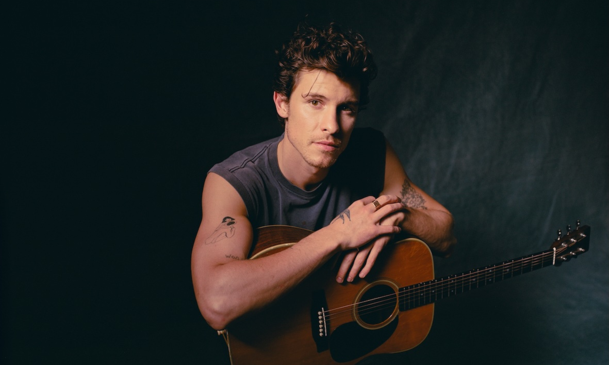 Sänger Shawn Mendes sitzt und lehnt sich auf seiner Gitarre ab
