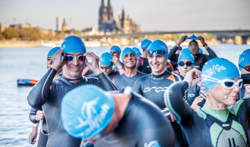 Das Foto zeigt Schwimmer beim Start des Kölntriathlons am Deutzer Hafen, im Hintergrund die Kulisse des Kölner Doms.