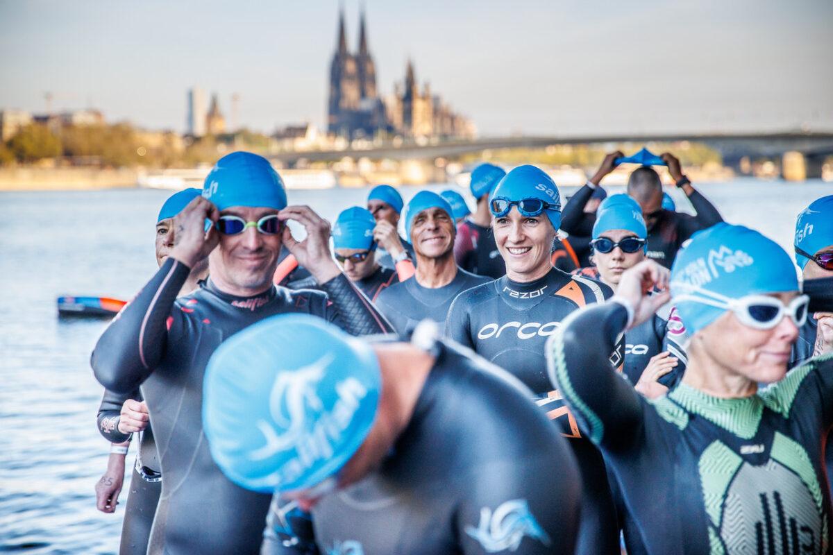 Das Foto zeigt Schwimmer beim Start des Kölntriathlons am Deutzer Hafen, im Hintergrund die Kulisse des Kölner Doms.