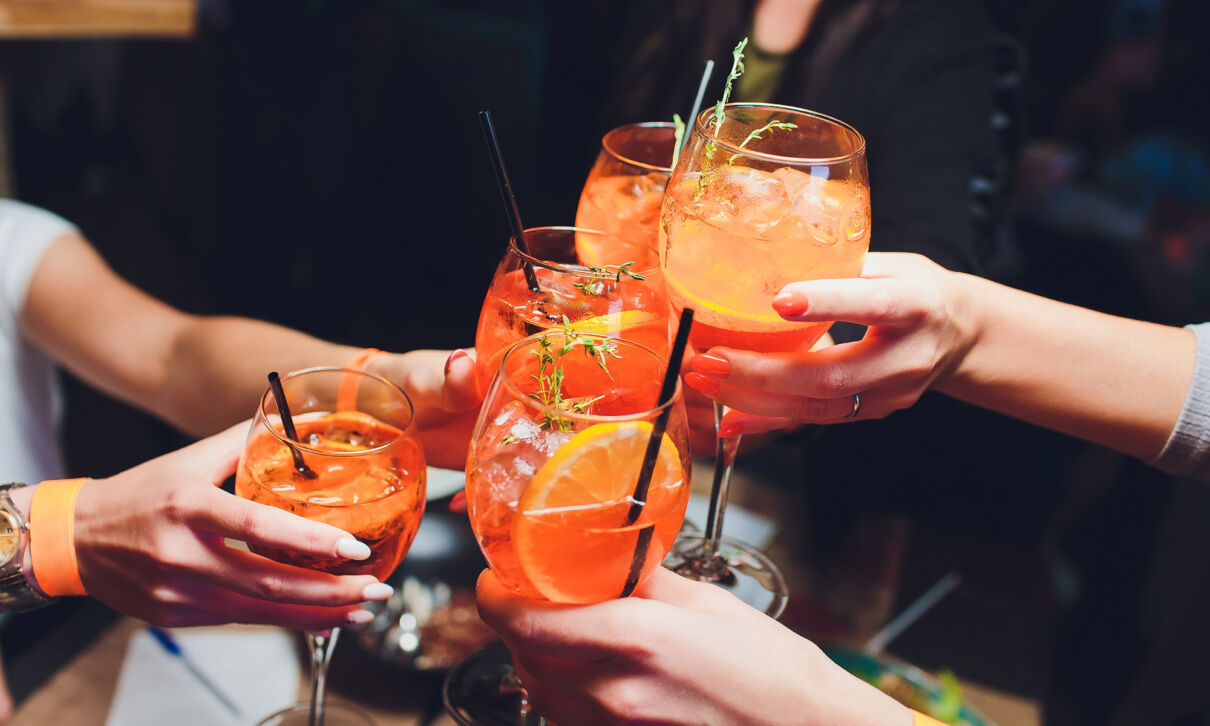 Menschen stoßen mit Aperol Spritz an.