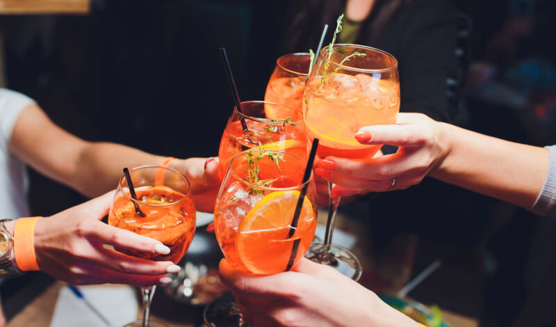 Menschen stoßen mit Aperol Spritz an.