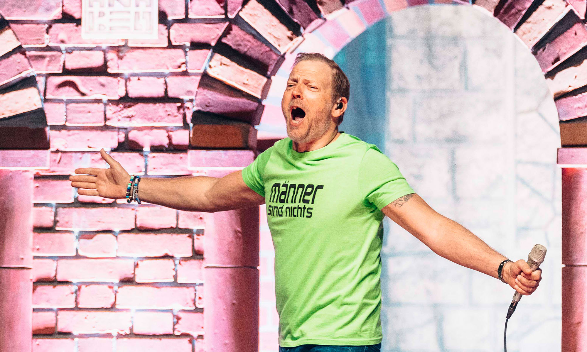 Der Comedian Mario Barth in einem grünen T-Shirt auf der Bühne.