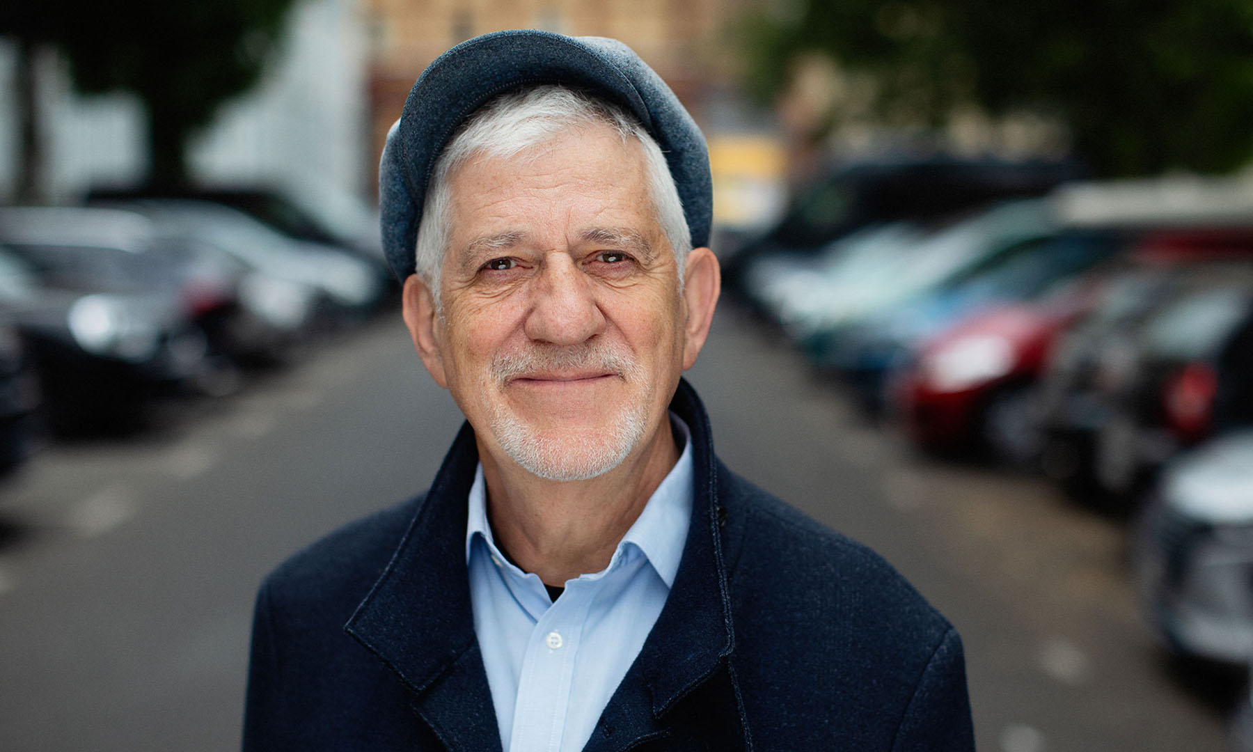 Ilja Richter steht mit einer Schiebermütze bekleidet auf einer Straße.