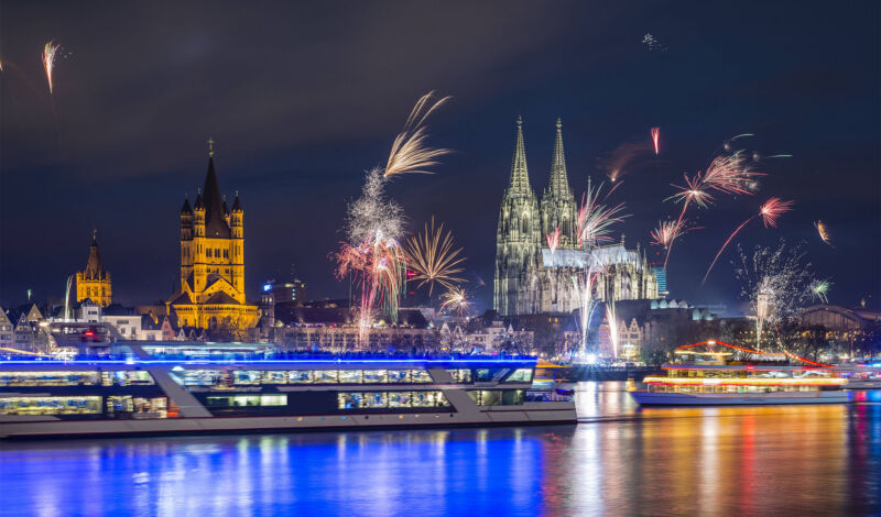 Ein Schiff fährt während des Silvesterfeuerwerks vor dem Panorama der Kölner Sltstadt vorbei