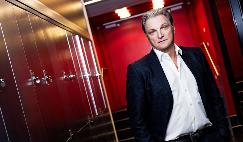 Der Schauspieler Stefan Jürgens steht in einem rotgefärbten Hotelflur.