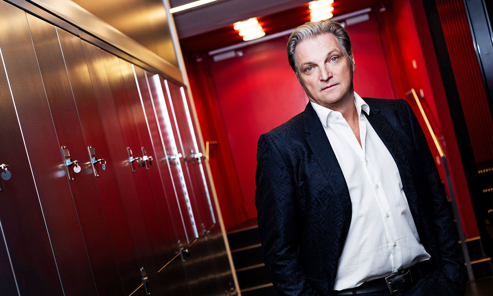 Der Schauspieler Stefan Jürgens steht in einem rotgefärbten Hotelflur.