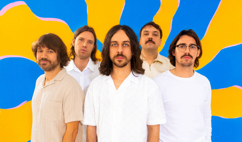 Die fünf Musiker der niederländisch-türkischen Rockgruppe Altın Gün vor blau-gelbem hintergrund.