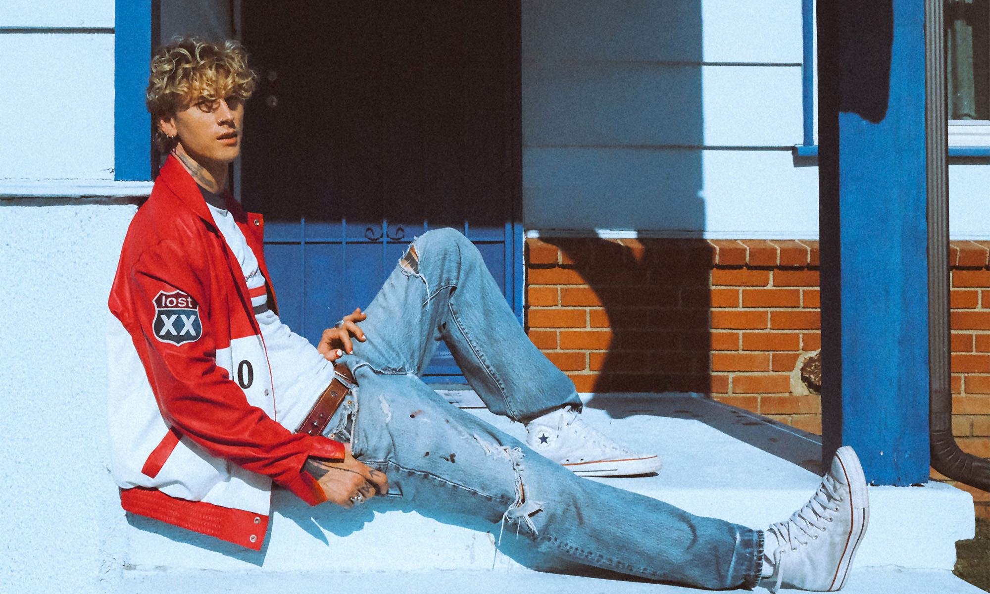 Der Sänger mgk (ehem. Machine Gun Kelly) sitzt auf einer Haustreppe.