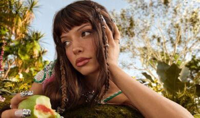 Die Sängerin Nina Chuba in einer exotischen Umgebung mit einer Frucht in der Hand