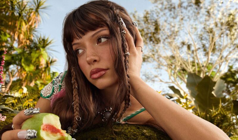 Die Sängerin Nina Chuba in einer exotischen Umgebung mit einer Frucht in der Hand