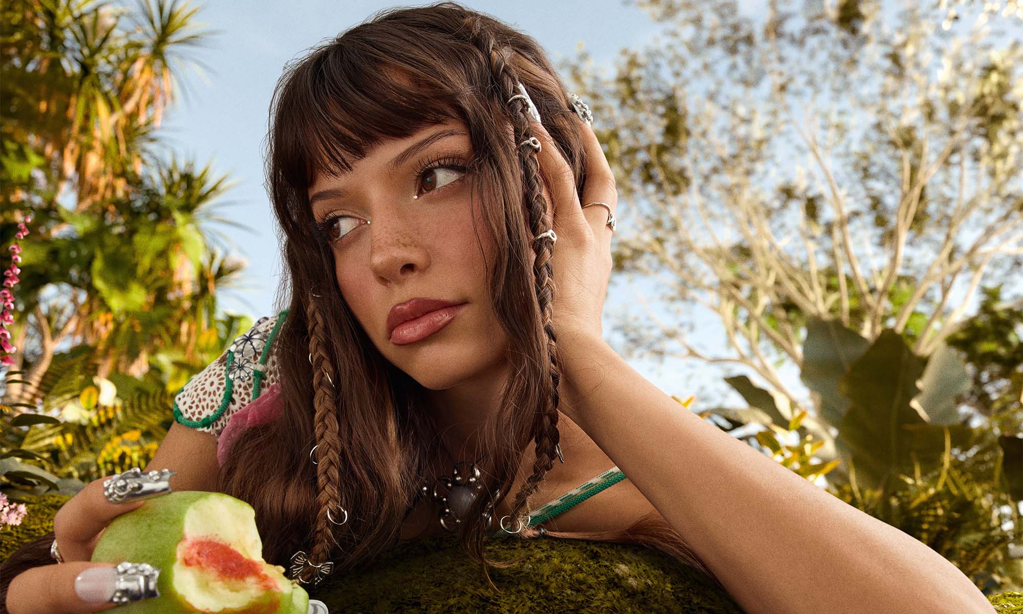 Die Sängerin Nina Chuba in einer exotischen Umgebung mit einer Frucht in der Hand