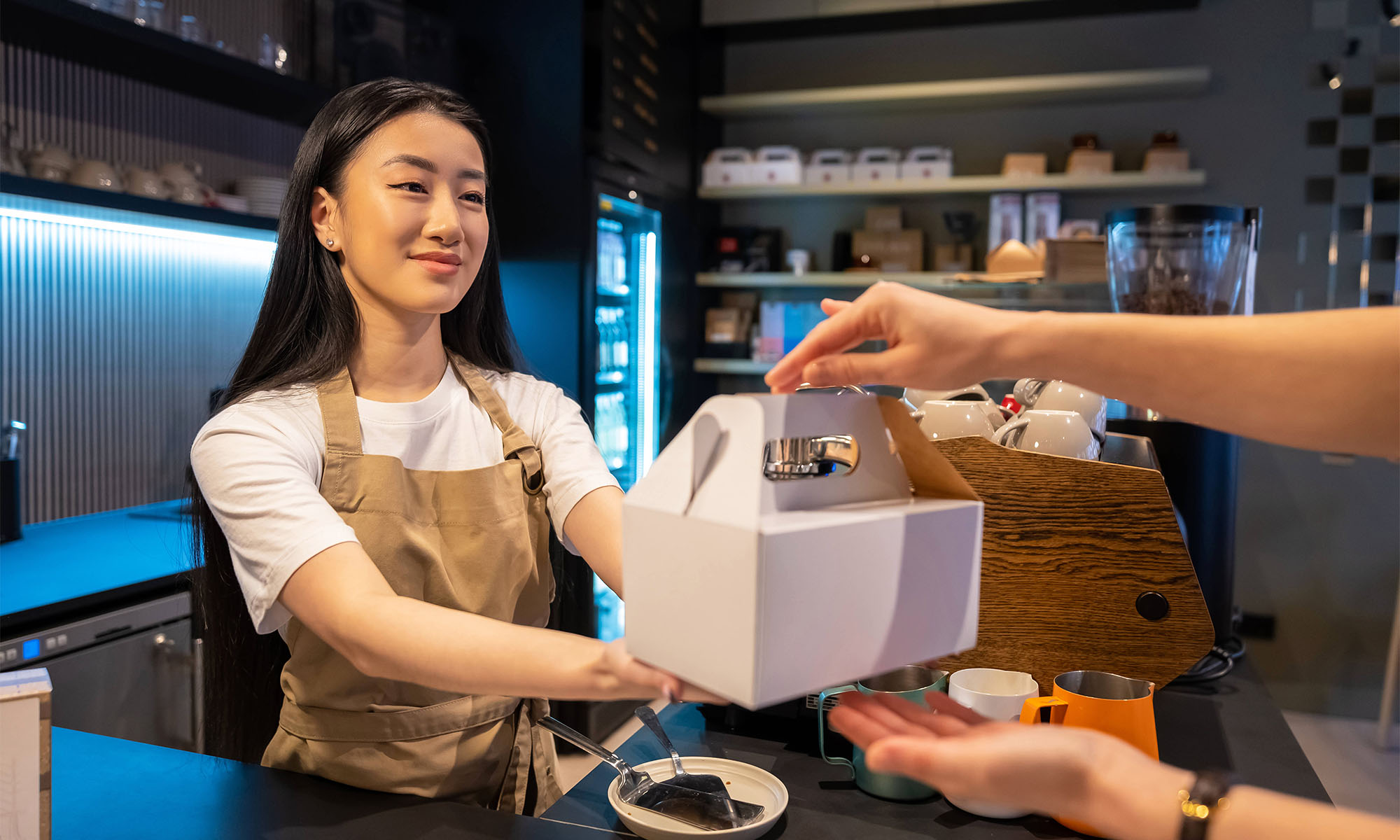 Eine Bedienung hinter der Theke eines Cafès reicht einem Kunden ein Paket