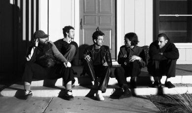 Die Mitglieder der Band The Neighbourhood sitzen auf einer Treppenstufe vor einem Hauseingang.