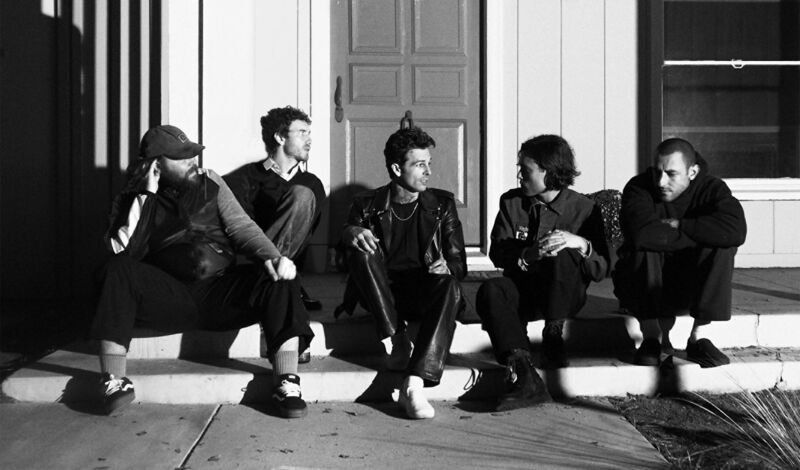 Die Mitglieder der Band The Neighbourhood sitzen auf einer Treppenstufe vor einem Hauseingang.