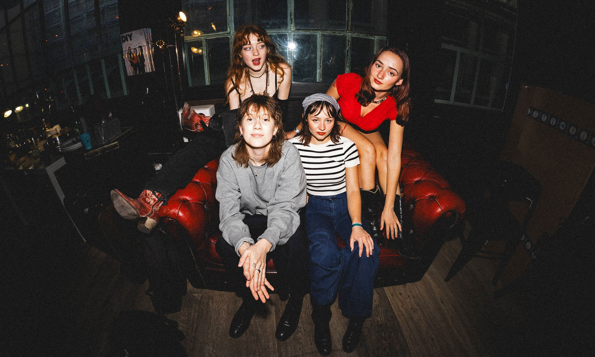 Die Musikerinnen der US-amerikanischen Rockband Die Spitz auf einem Sofa in einem abgedunkelten Raum.