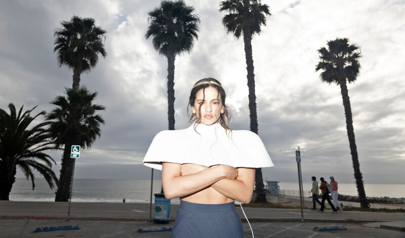 Die spanische Sängerin Rosalía steht vor Palmen.