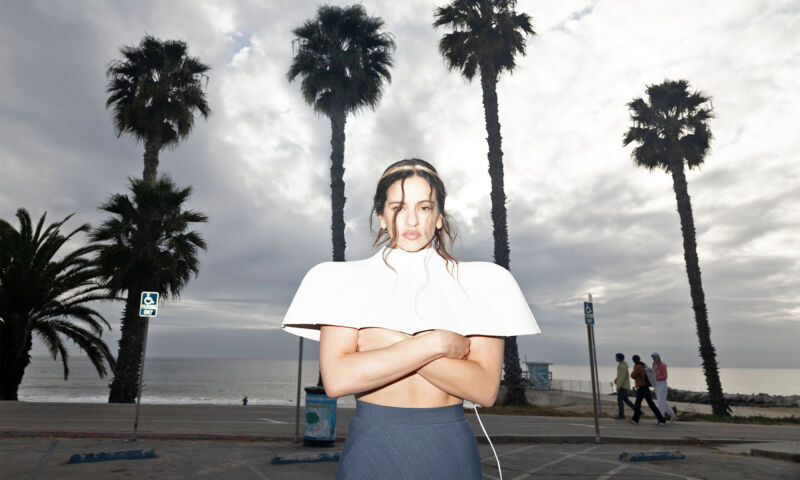 Die spanische Sängerin Rosalía steht vor Palmen.