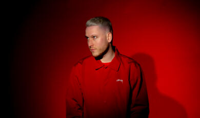 Der Kölner Rapper Mo-Torrs in roter Kleidung vor rotem Hintergrund.