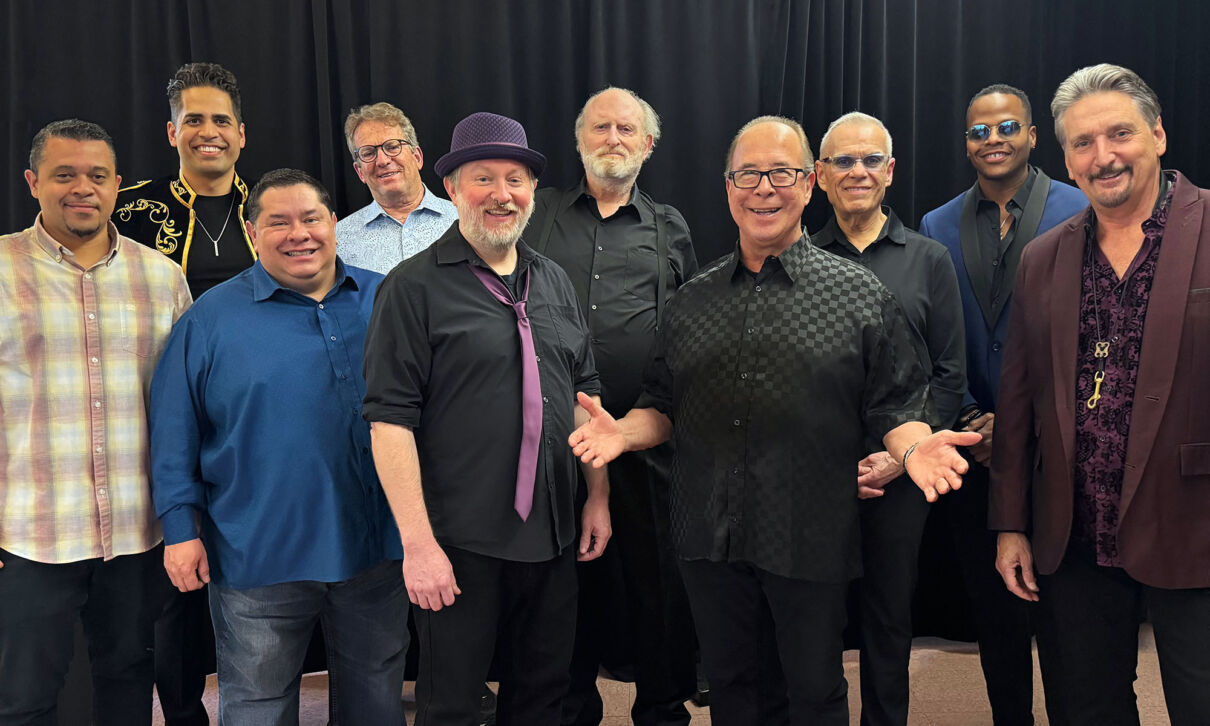 Die Musiker der Band Tower of Power stehen vor schwarzem Hintergrund.