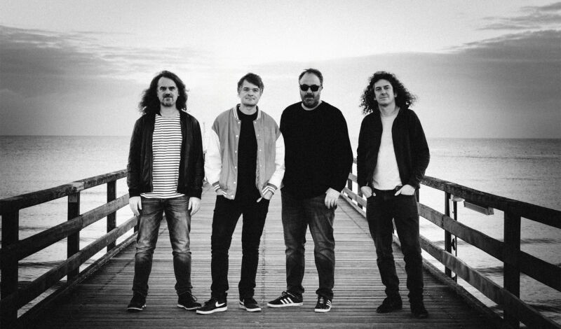 Die vier Mitglieder der deutschen Rockband Madsen stehen auf einem Steg.