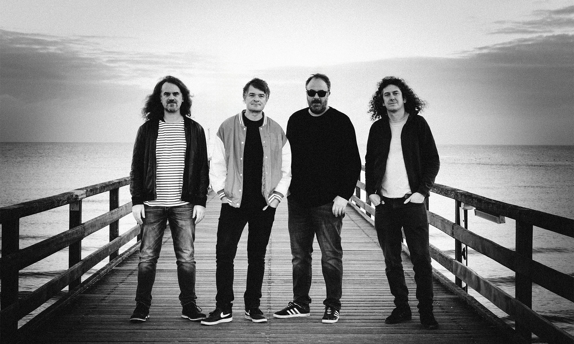 Die vier Mitglieder der deutschen Rockband Madsen stehen auf einem Steg.