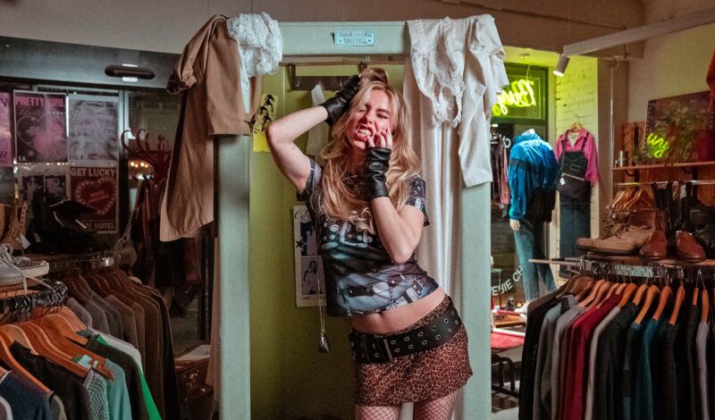 Die Sängerin Eileen Alister steht inmitten von Kleidung in einem bekleidungsgeschäft.