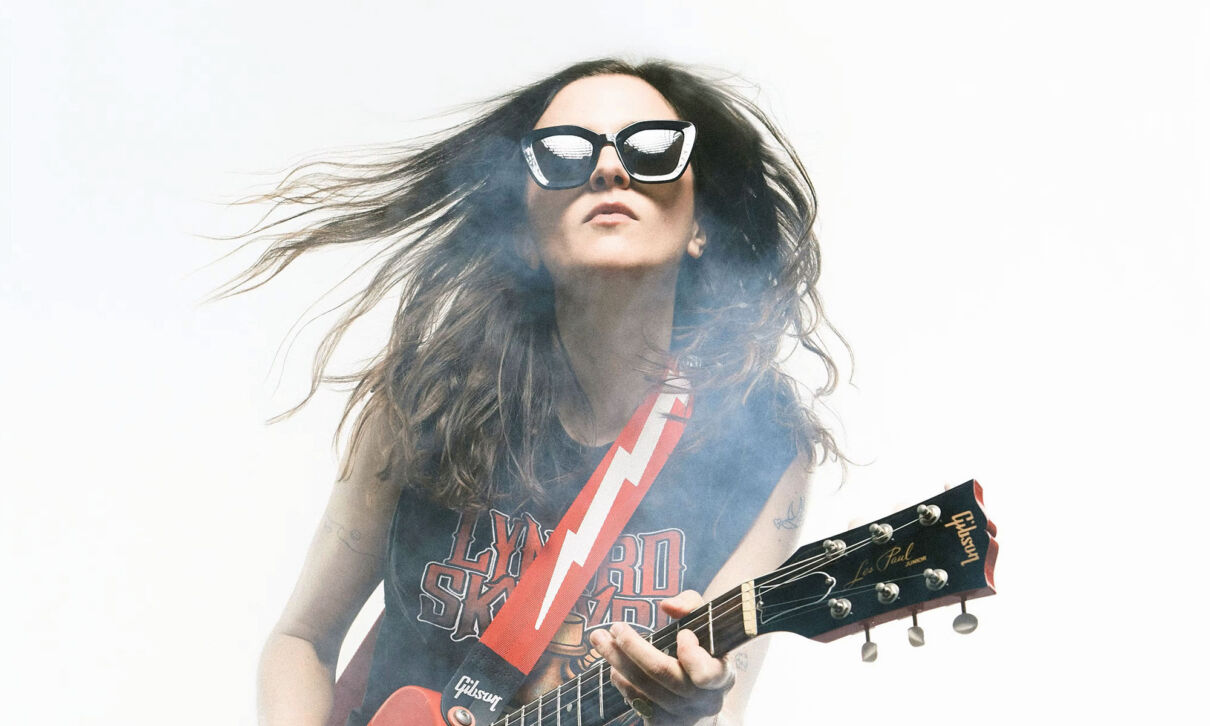 Die französische Gitarristin Laura Cox mit Sonnenbrille und Gitarre