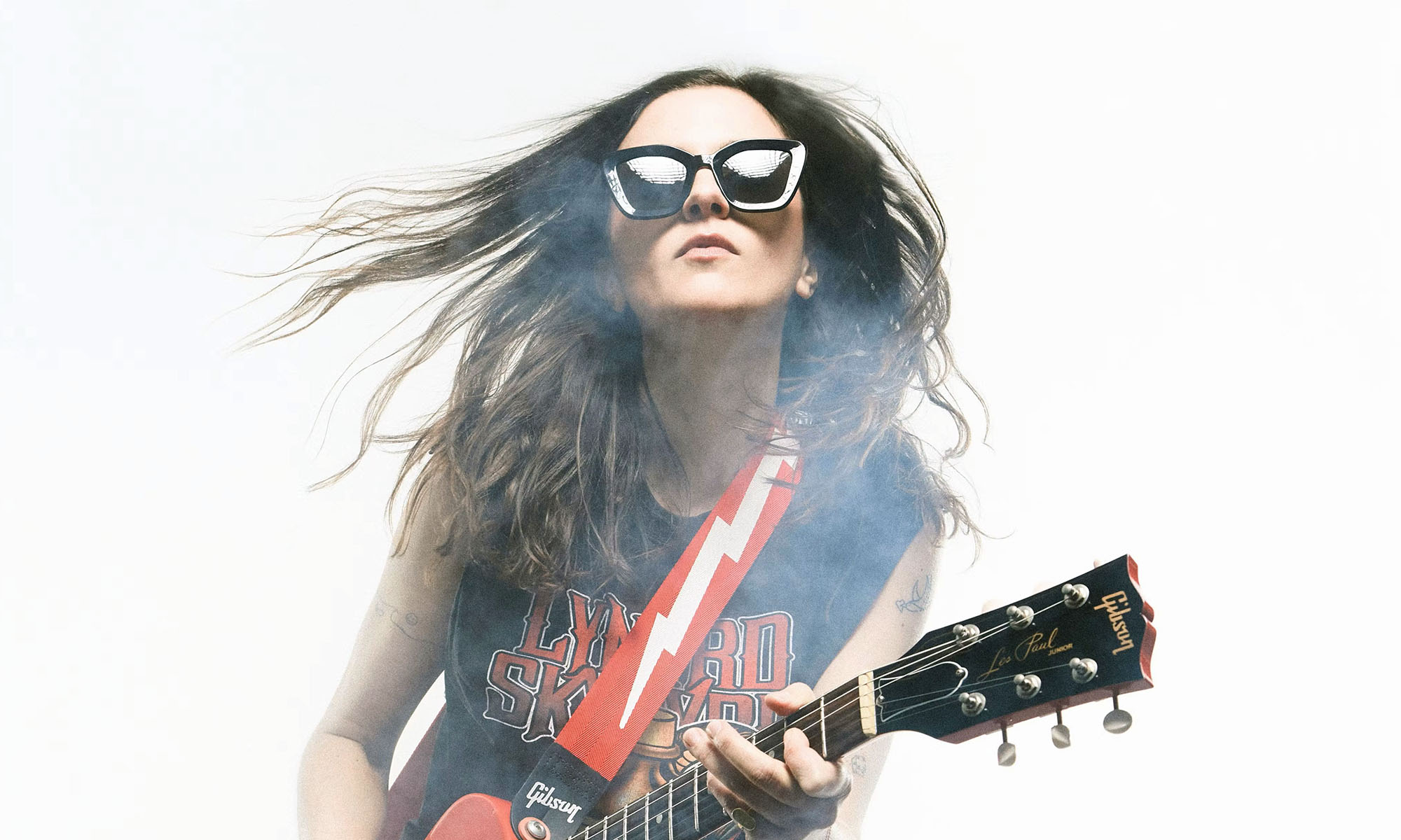 Die französische Gitarristin Laura Cox mit Sonnenbrille und Gitarre