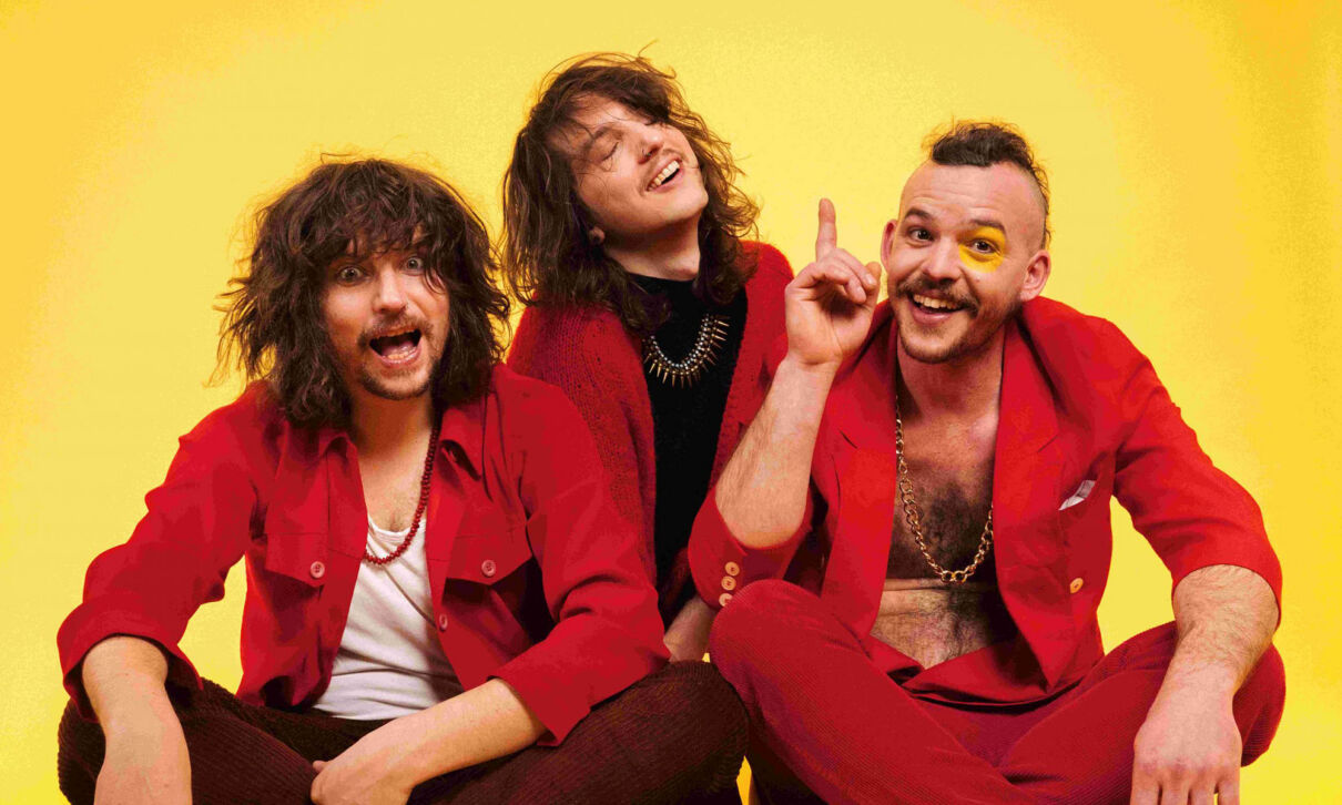 Die Musiker der österreichischen Psychedeloc-Rockband Mother's Cake in roter Kleidung vor gelbem hintergrund