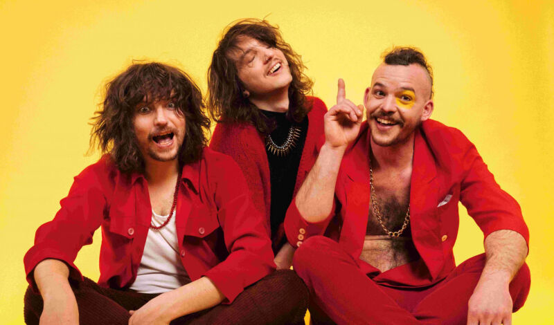 Die Musiker der österreichischen Psychedeloc-Rockband Mother's Cake in roter Kleidung vor gelbem hintergrund