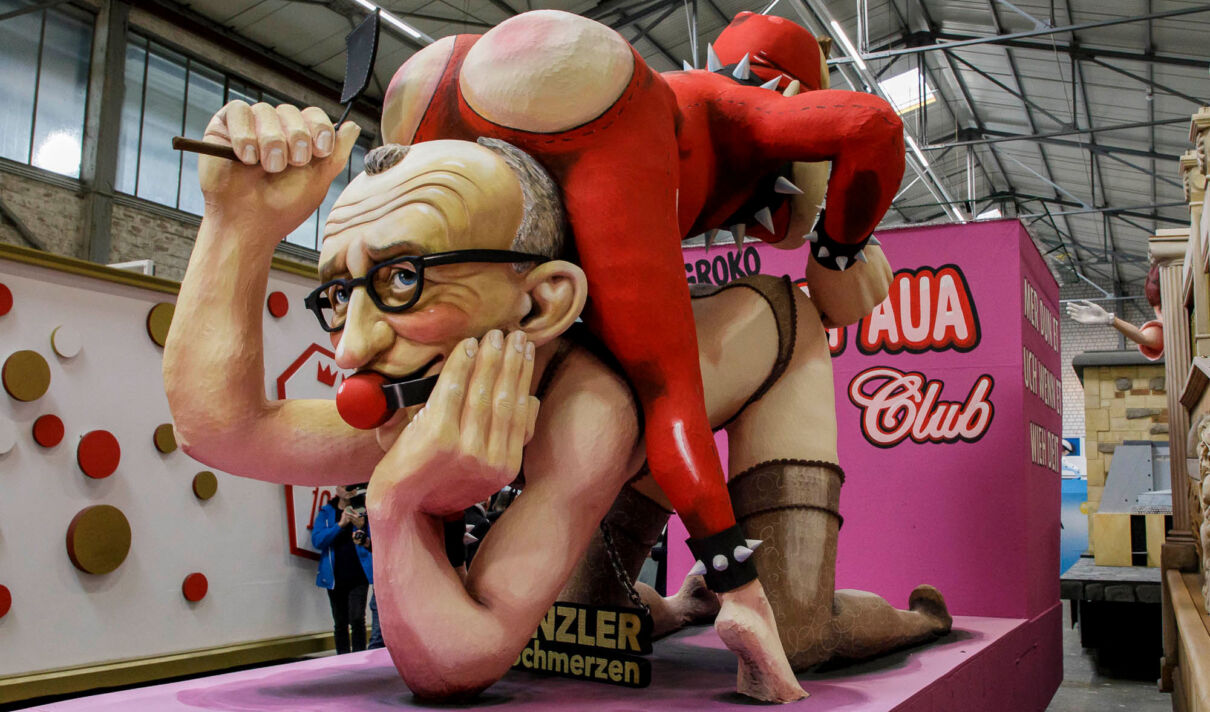 Eine anzügliche Karikatur von Friedrich Merz und Lars Klingbeil, die als Persiflagewagen im Kölner Rosenmontagszug 2026 fährt.