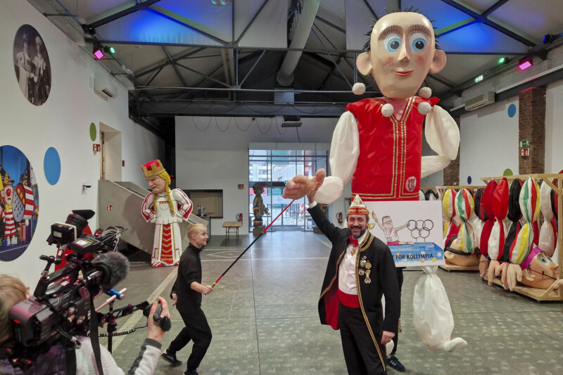 Zugleiter Marc Michelske präsentiert Motive von Persiflagewagen im Kölner Rosenmontagszug der Session 2026