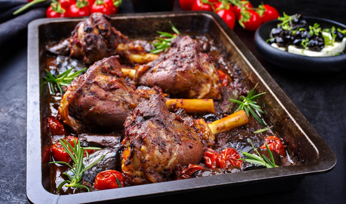 Mehrere gegrillte Lammhaxen mit Gemüse auf einem Backofenblech