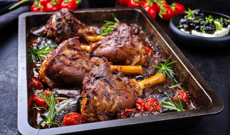 Mehrere gegrillte Lammhaxen mit Gemüse auf einem Backofenblech