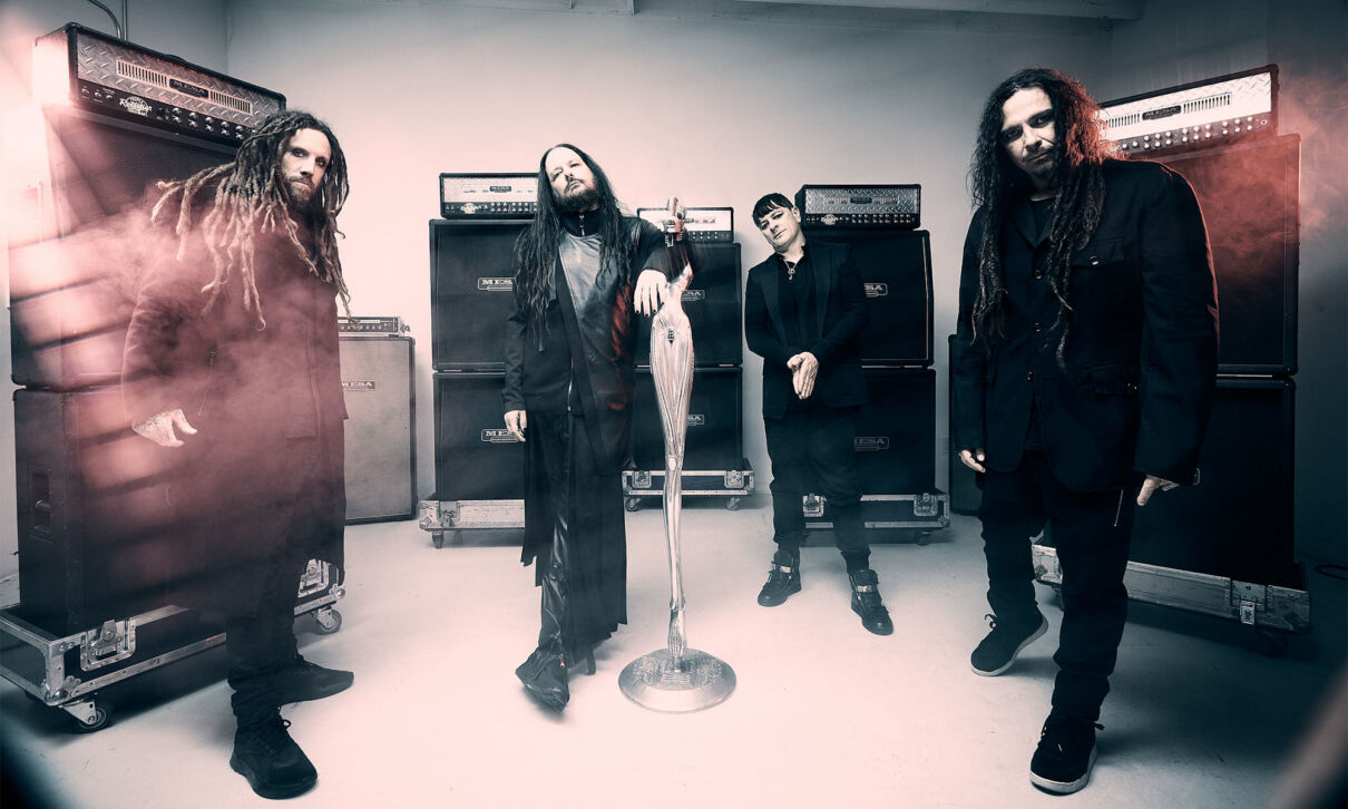 Musiker der Nu-Metal-Band Korn stehen vor Gitarrenverstärkern.