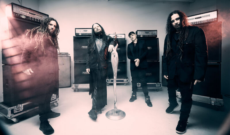 Musiker der Nu-Metal-Band Korn stehen vor Gitarrenverstärkern.