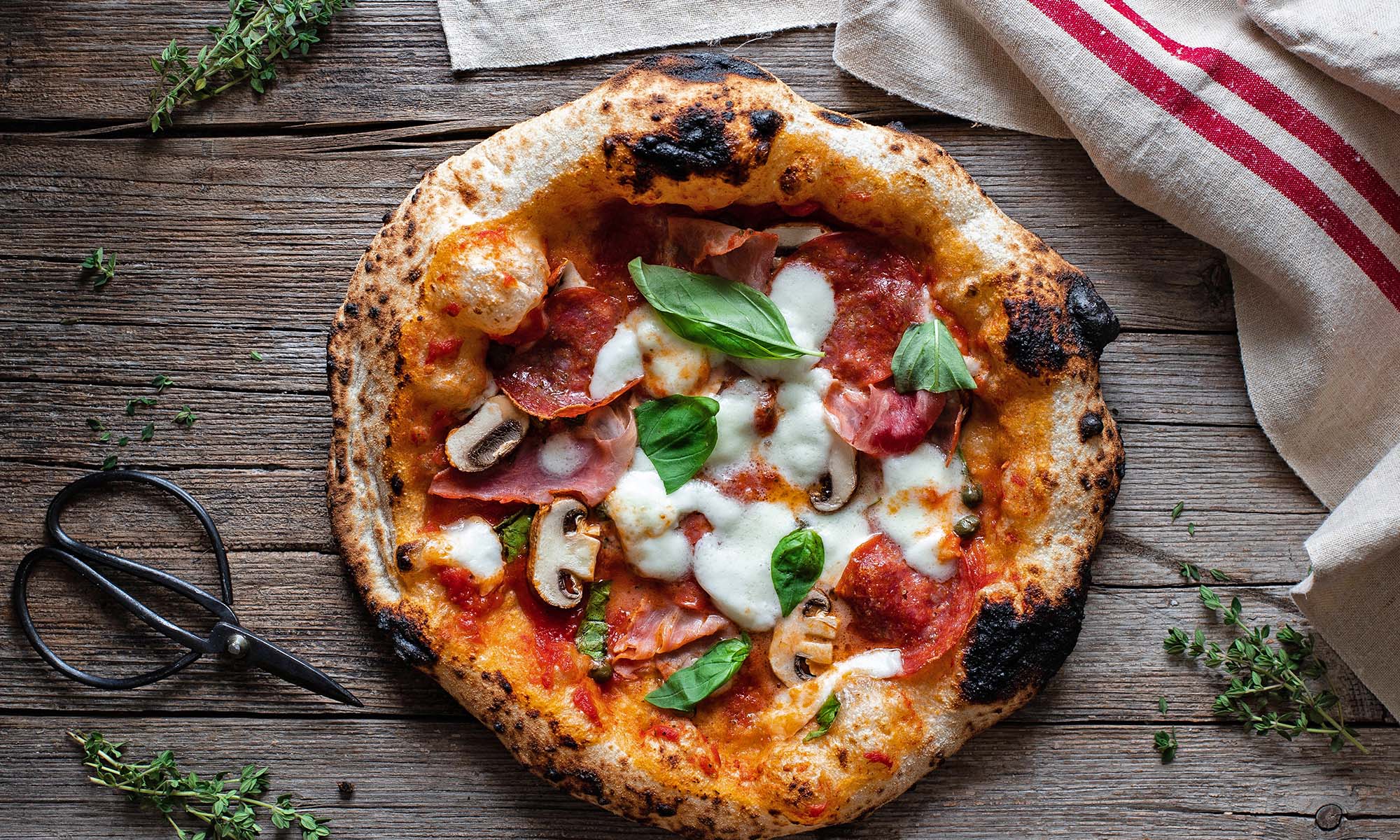 Eine Pizza Neapolitana mit breitem Rand und Tomate, Mozzarella und Basilikum