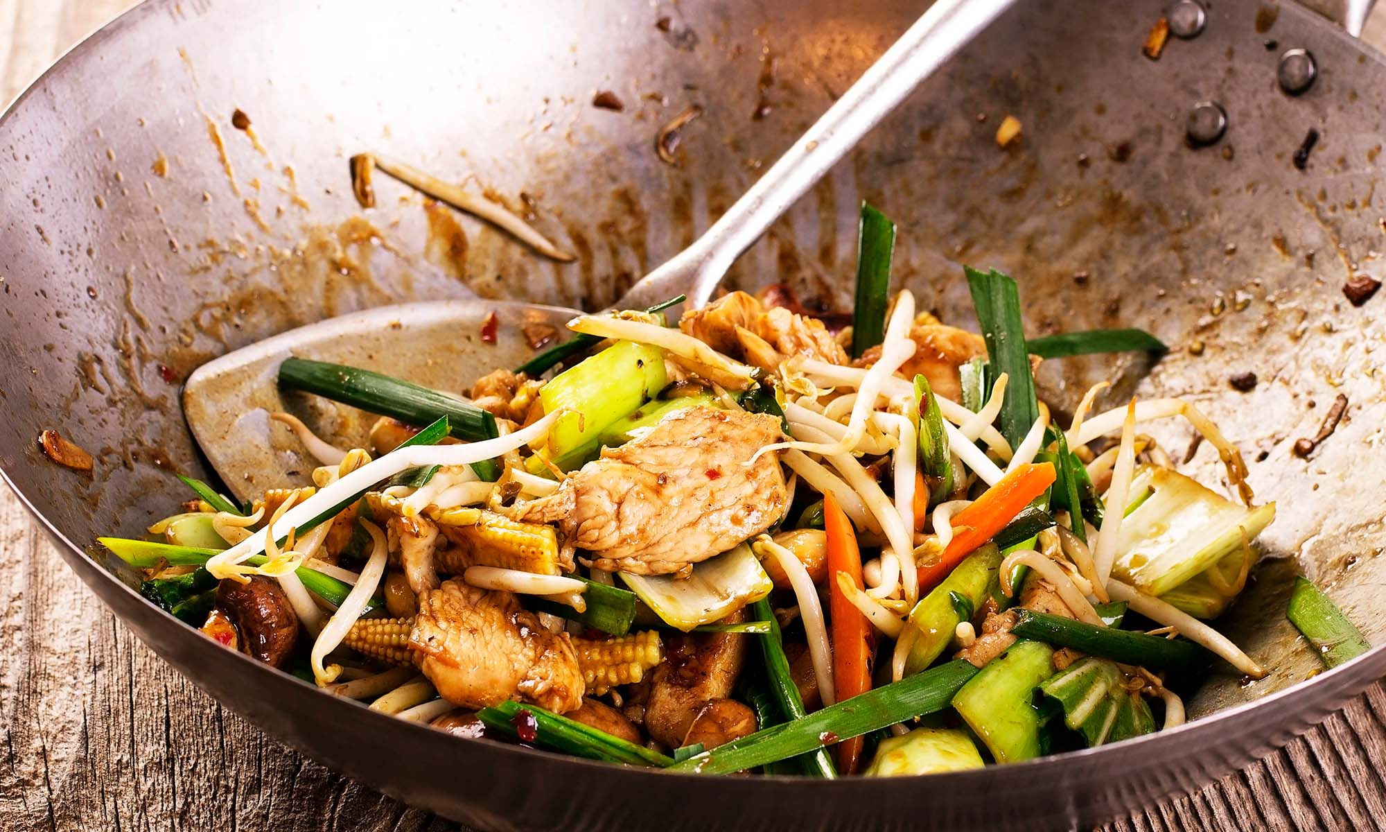 In einem Wok wird Gemüse zusammen mit Hähnchenfleisch gegart.
