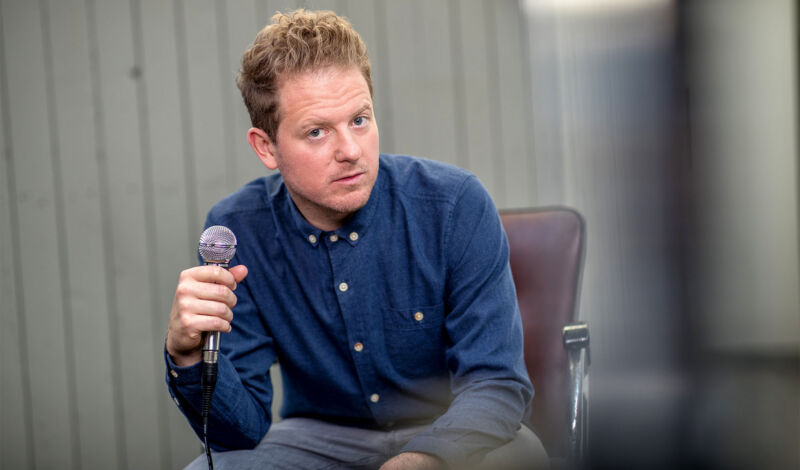 Der Kabarettist Martin Zingsheim mit Mikrofon auf einem Sessel.