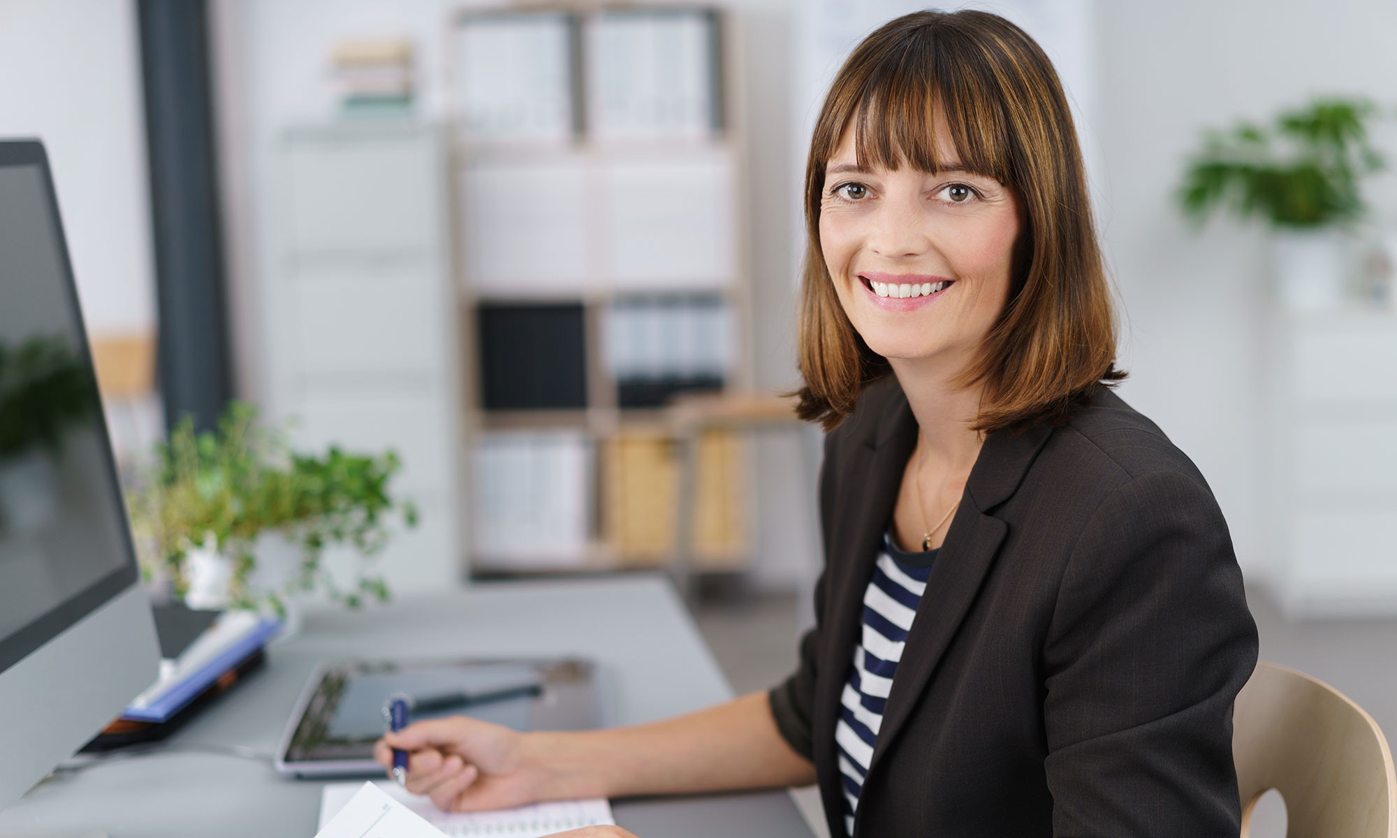Eine Junge Frau im Büro an einem Bildschirmarbeitsplatz