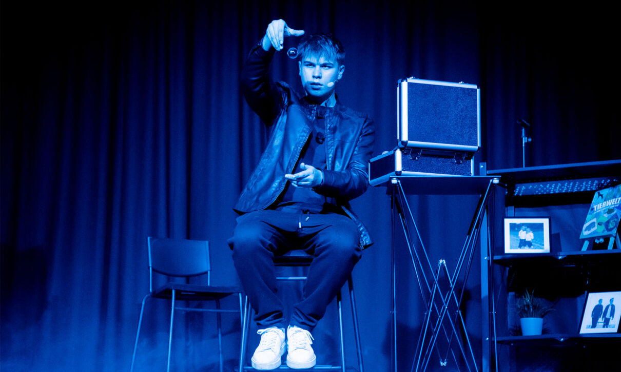Ein Zauberer aus der Zaubershow twoMagic in bleuem Licht auf der Bühne