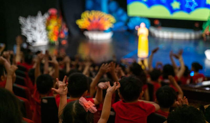 Kinder sitzen in einem Theater und schauen auf die Bühne