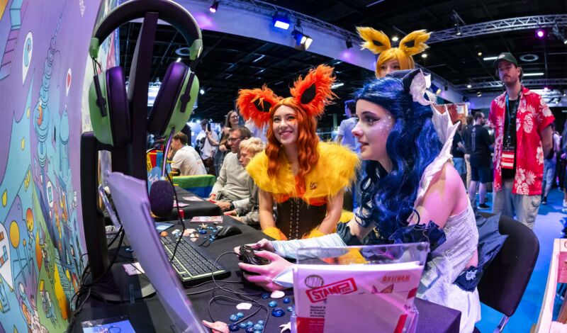 Besucherinnen im Cosplay-Outfit testen auf der Gamescom Spielekonsolen.