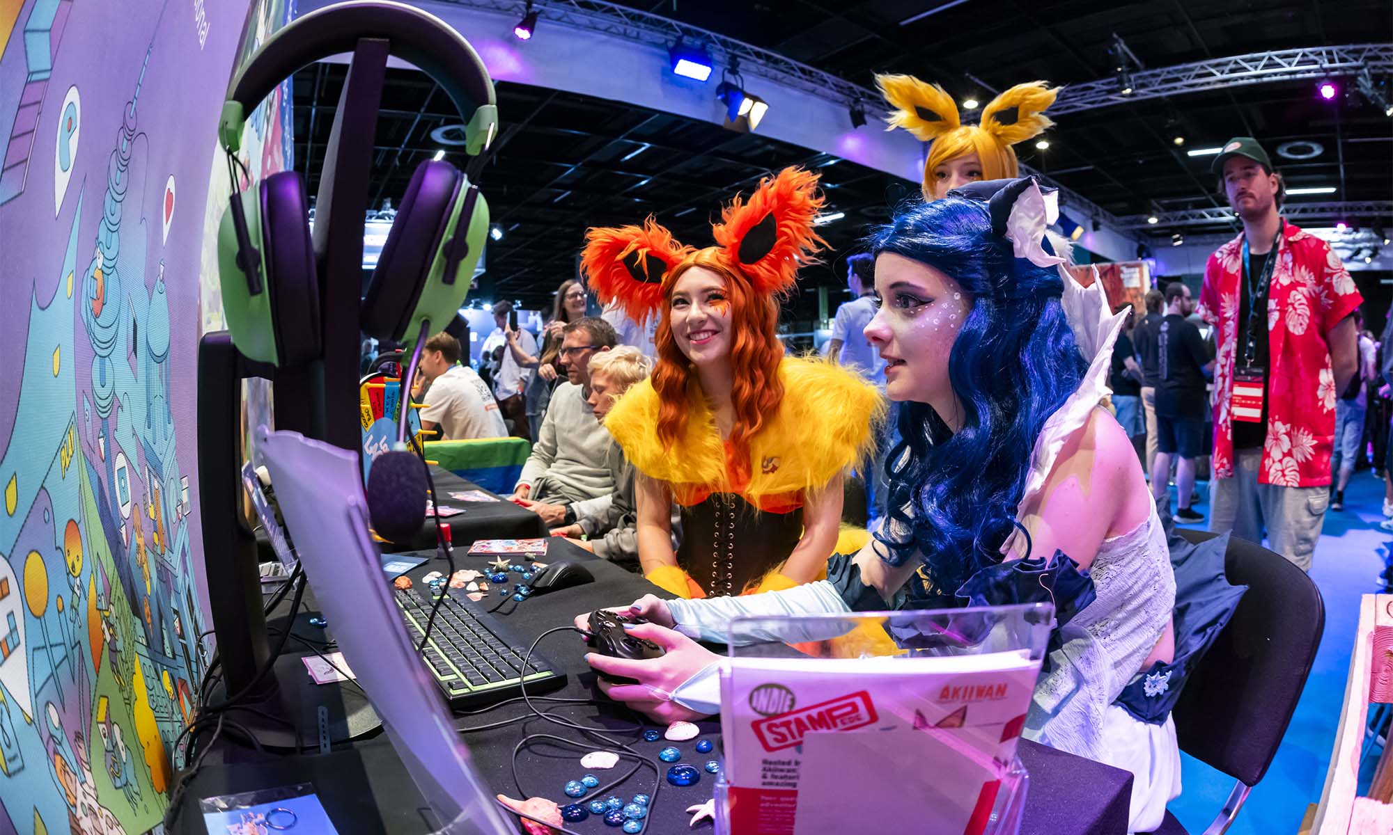 Besucherinnen im Cosplay-Outfit testen auf der Gamescom Spielekonsolen.