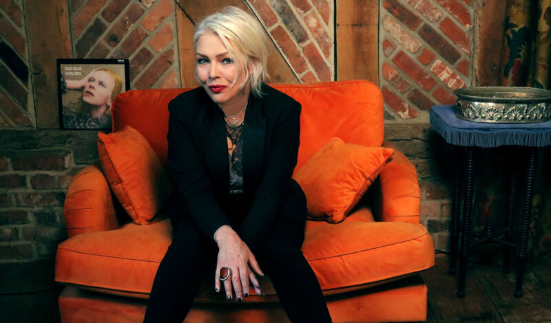 Die britische Sängerin Kim Wilde sitzt auf einem orangen Sofa.