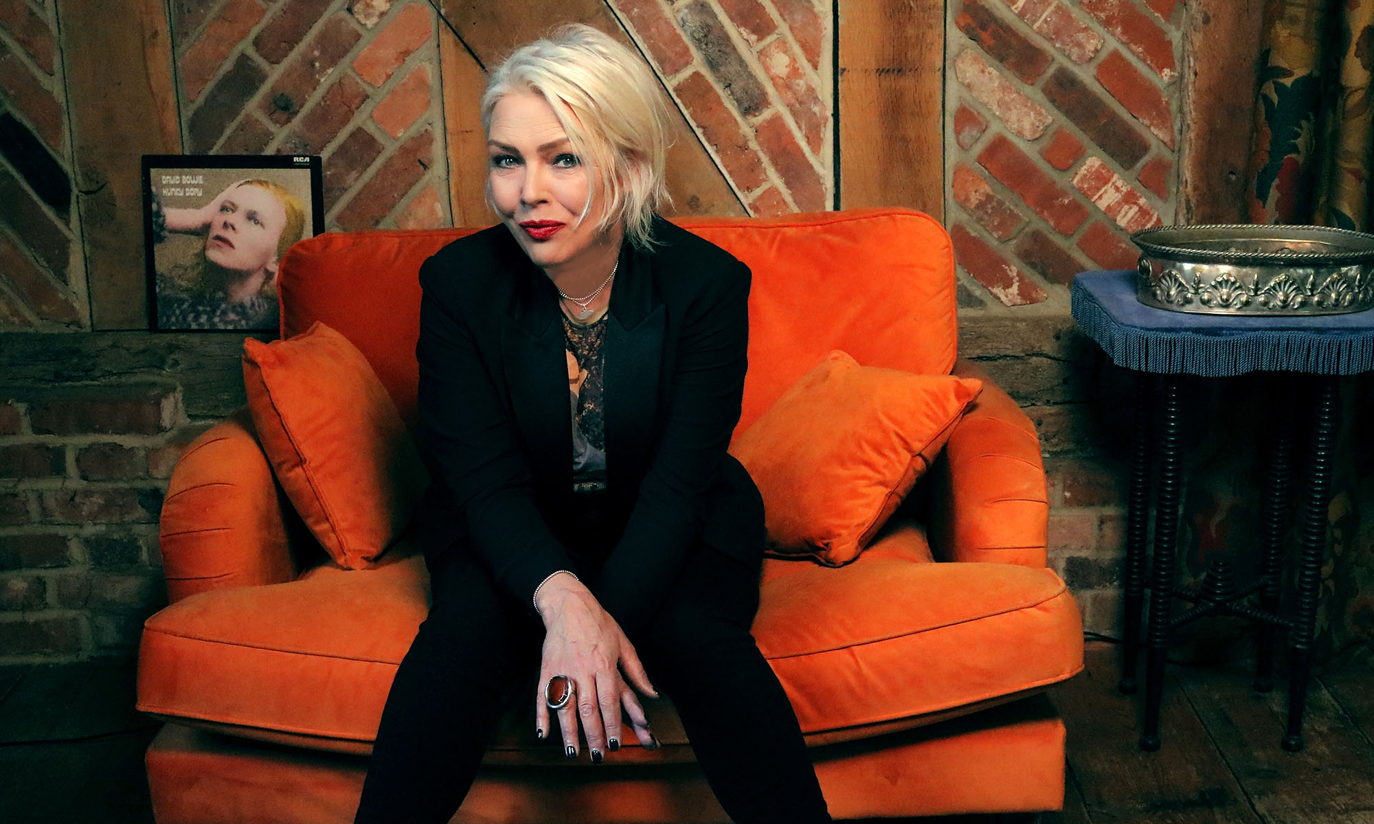 Die britische Sängerin Kim Wilde sitzt auf einem orangen Sofa.