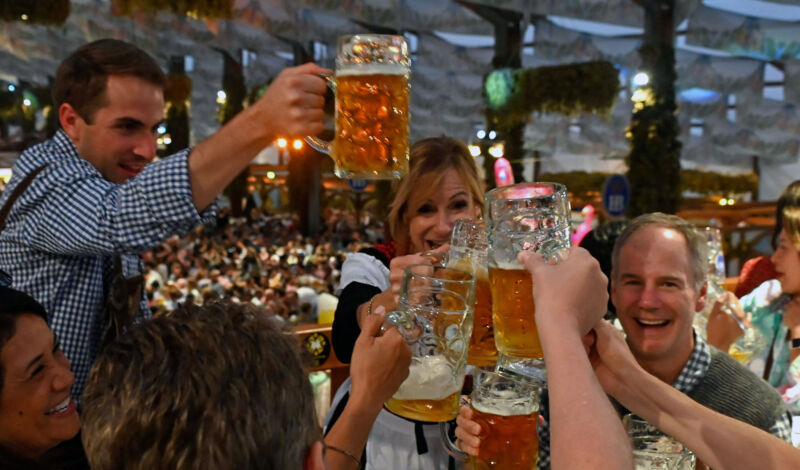 Feiernde stoßen auf dem oktoberfest mit Bier in Maßkrügen an