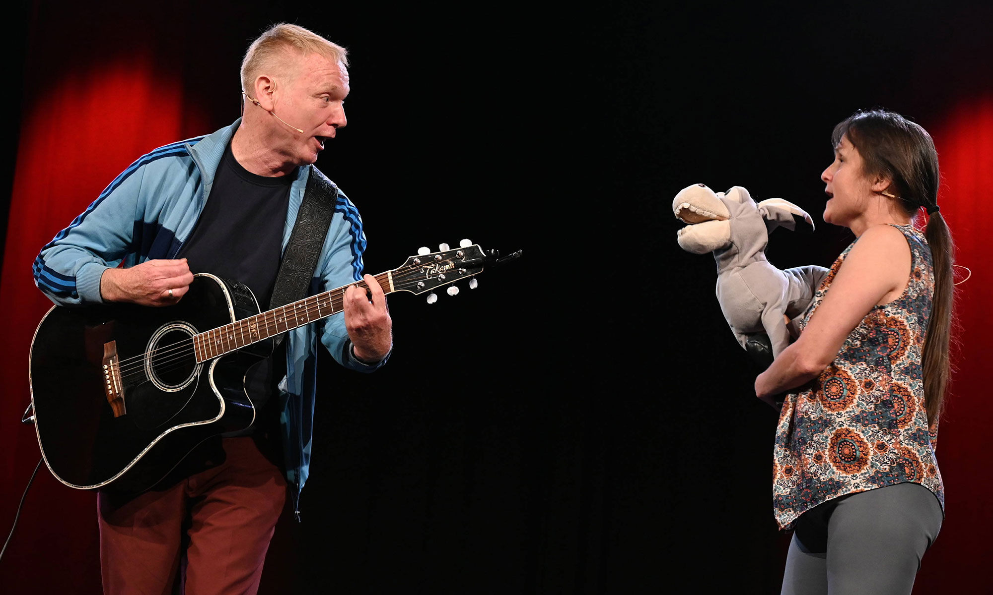 Zwei Schauspieler mit Gitarre und Esel-Handpuppe auf der Bühne.